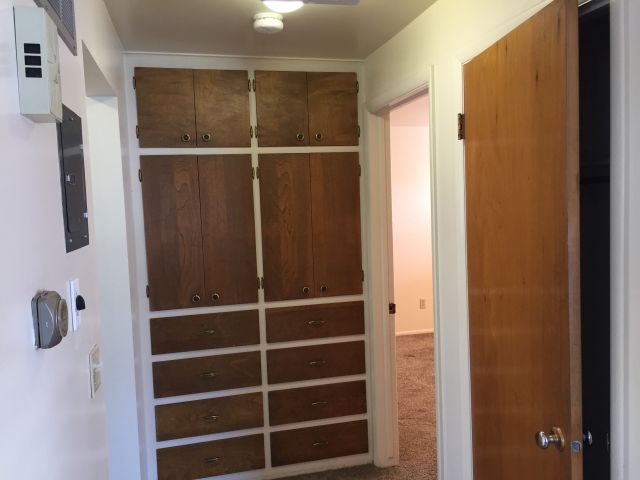 Hallway with built-in cabinets and coat closet