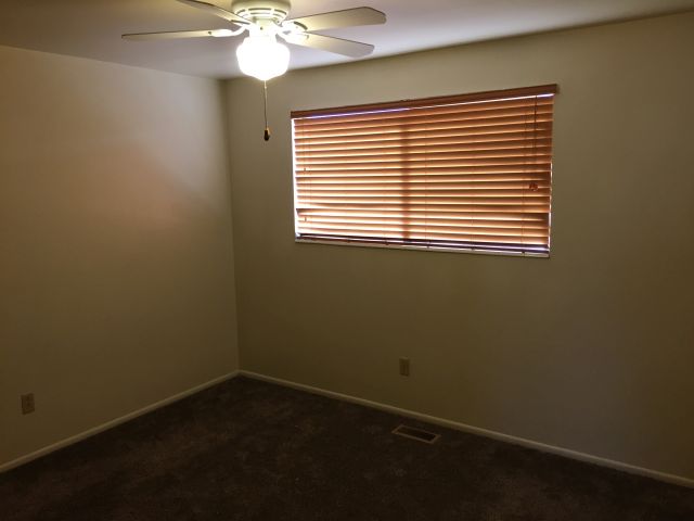 Bedroom with large window and ceiling fan