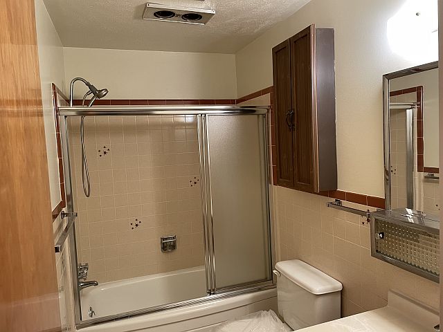 Bathroom has shower wand, heat lamps and tub doors