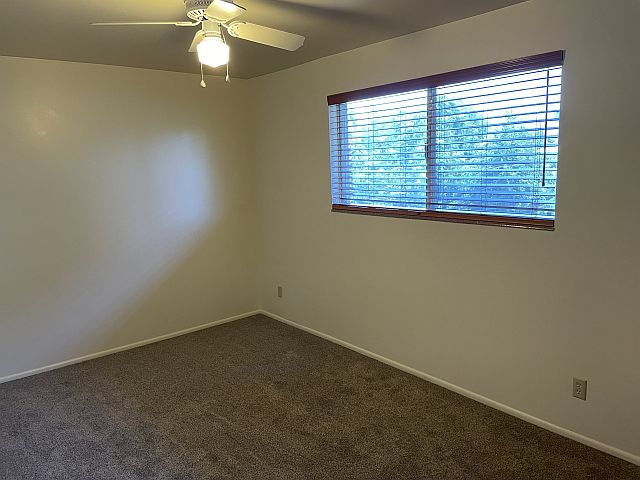 Bedroom has large window & ceiling fan