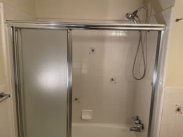 Bath has tub doors, heat lamps, shower wand & vent fan