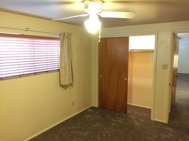 Bedroom has large lighted closet, ceiling fan, window blinds & drapes